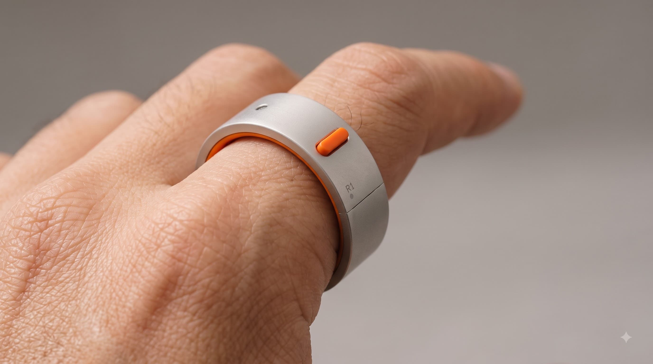 The Rhyme R1 ring worn on an index finger, its orange button under the thumb